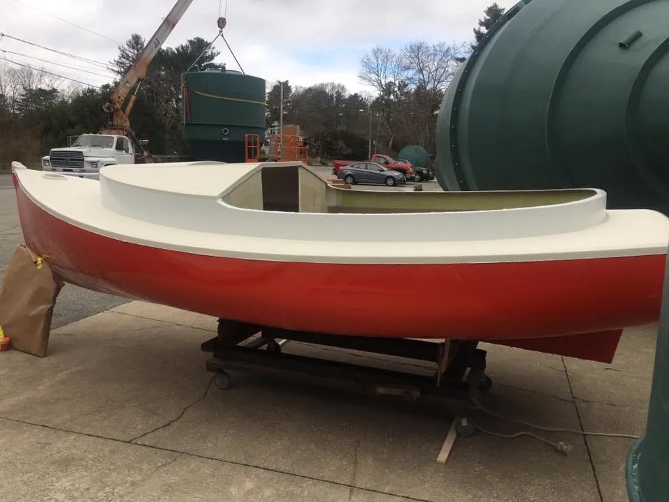 A red and white boat is sitting in a parking lot