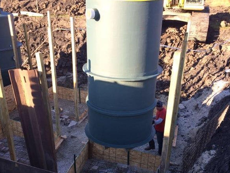 A man is standing next to a large metal cylinder in the dirt.