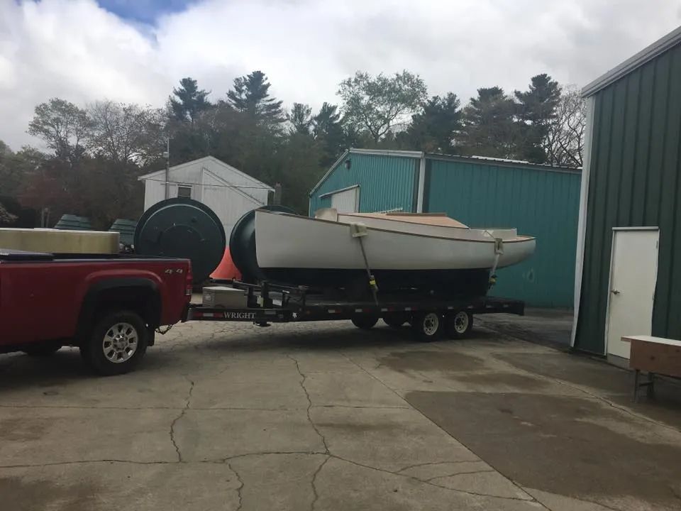 A red truck is pulling a boat on a trailer