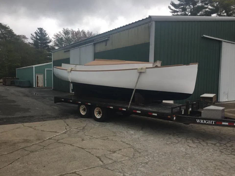 A boat is on a trailer in front of a green building