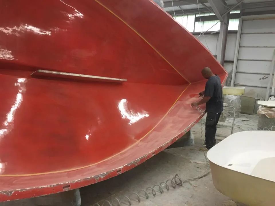 A man is working on a large red object in a factory.