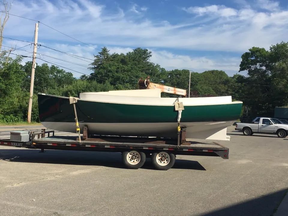 A green and white boat is on a trailer