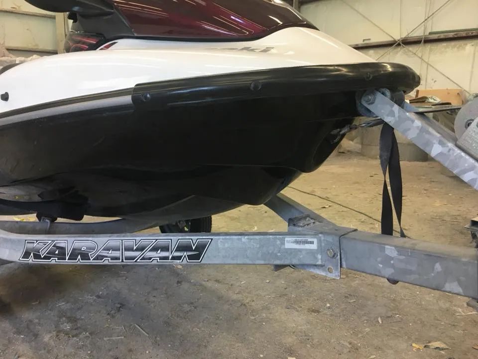 A jet ski is sitting on a trailer in a garage.