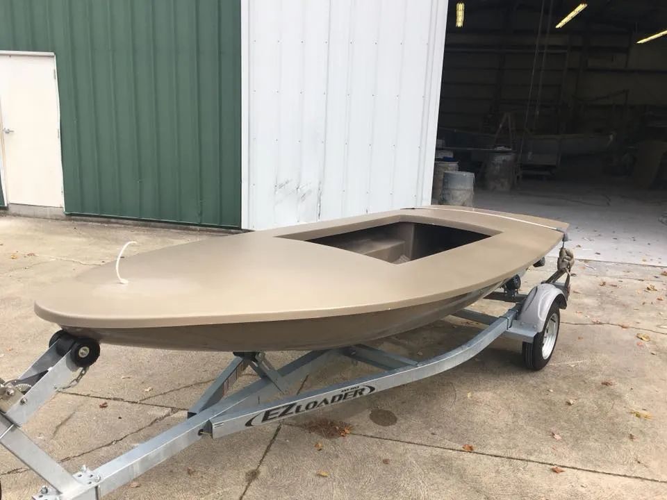 A small boat is on a trailer in front of a building.