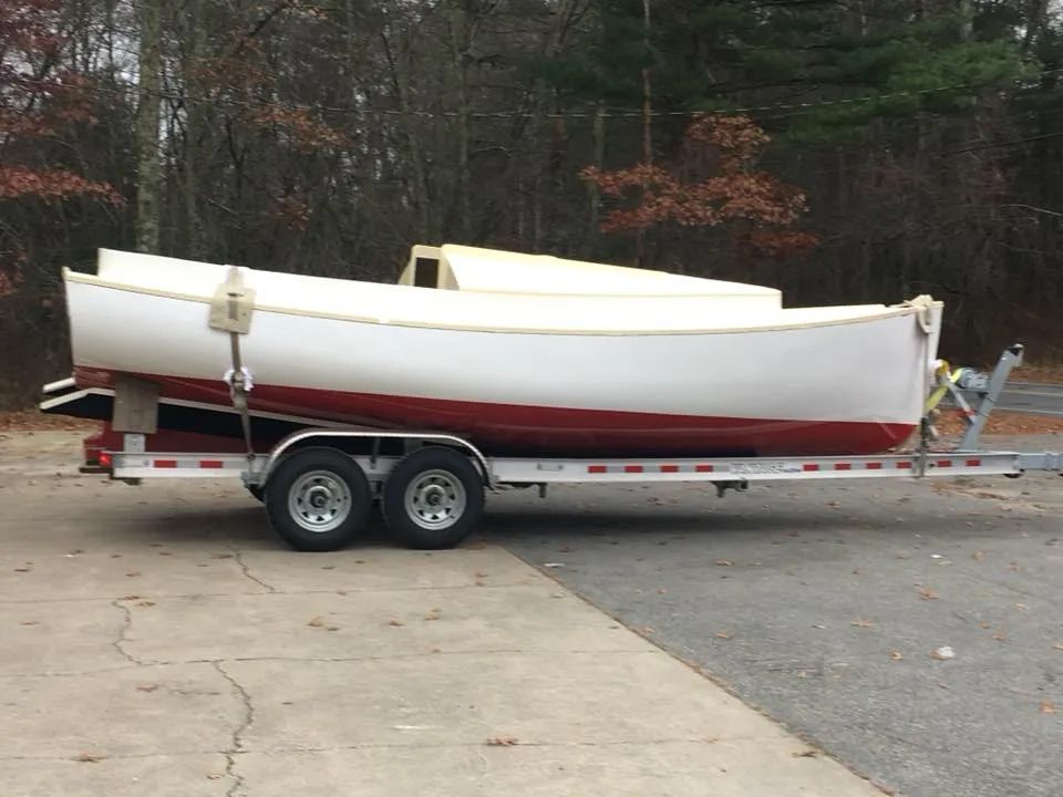 A boat is on a trailer in a parking lot.