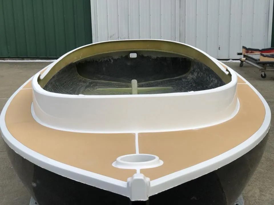 A small boat with a wooden deck is sitting on the ground