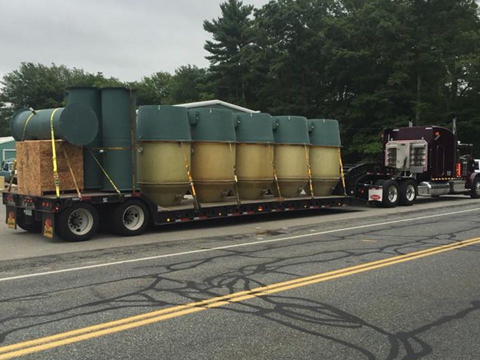 A semi truck is pulling a trailer full of containers down a road.