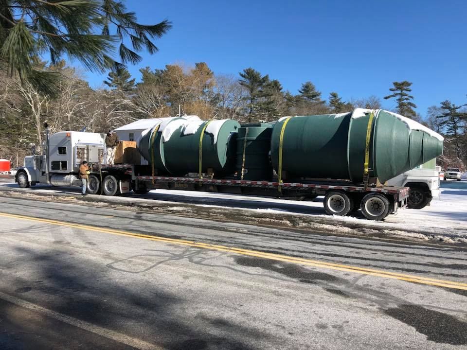 A semi truck is carrying a large green object down a snowy road.