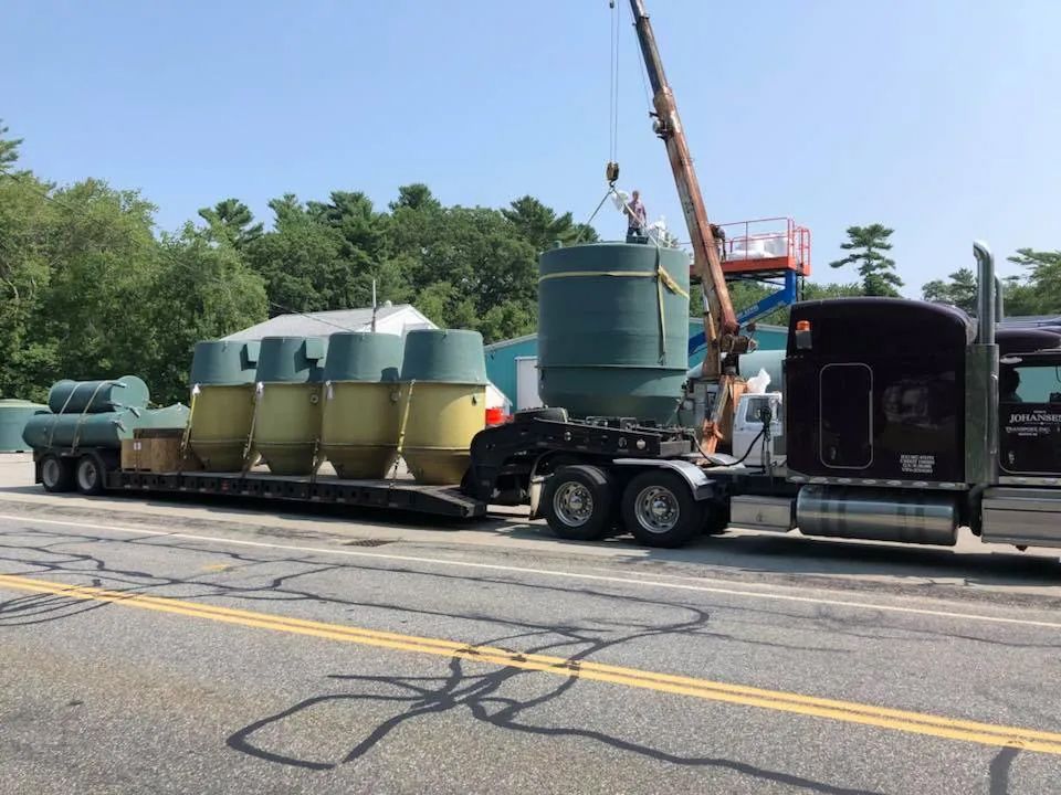 A semi truck is being towed down a road by a crane.
