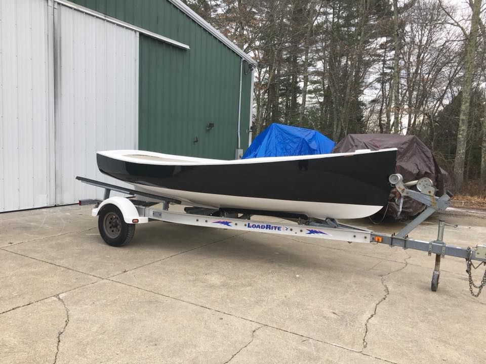 A boat is on a trailer in front of a green building