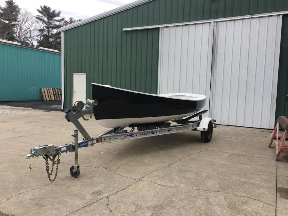 A boat is on a trailer in front of a green building.