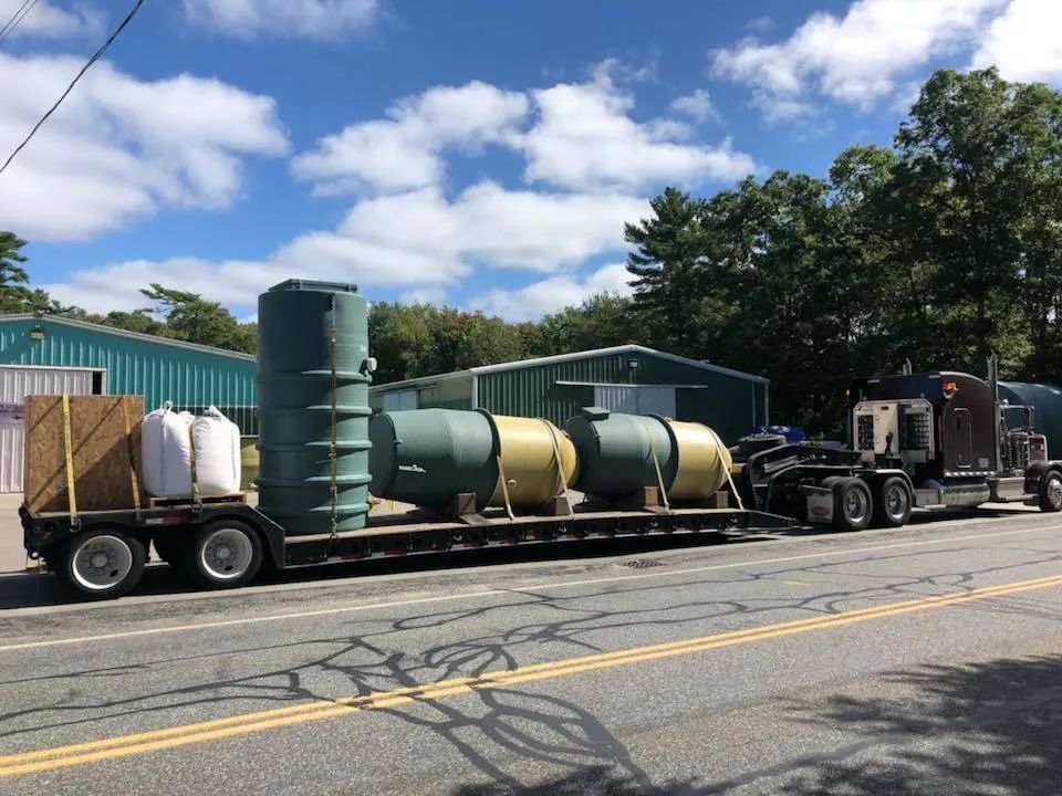 A semi truck is carrying large tanks down a road.