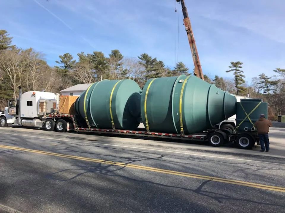 A large green tank is being loaded on a semi truck.