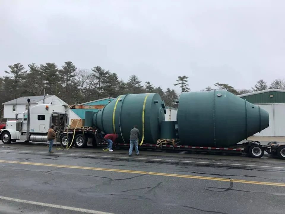 A large green object is being loaded on a semi truck.