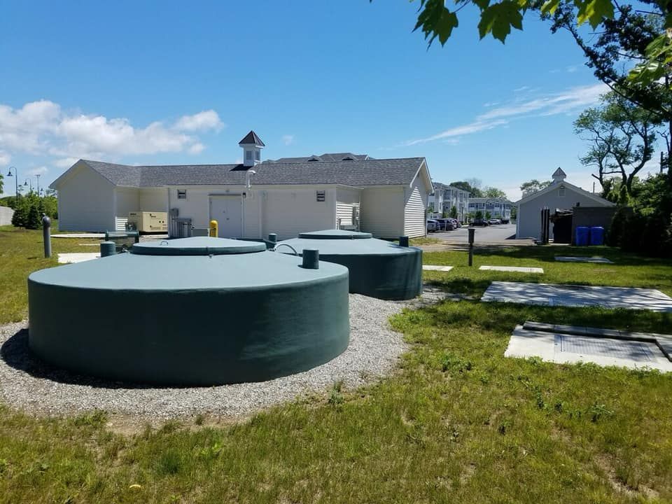 A row of green tanks in a grassy field in front of a building