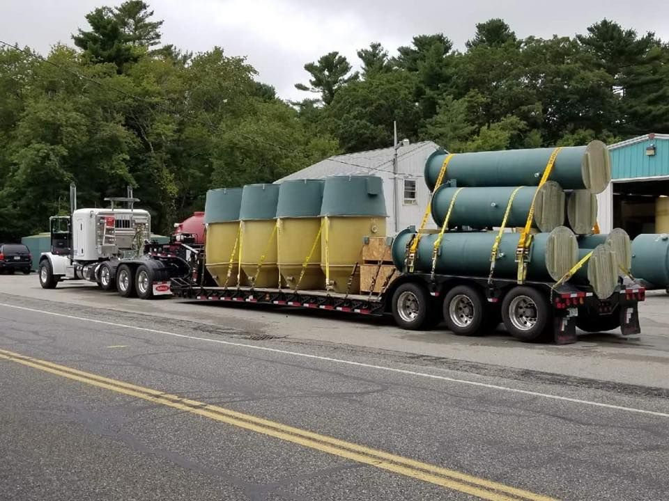 A semi truck is pulling a trailer with a bunch of tanks on it