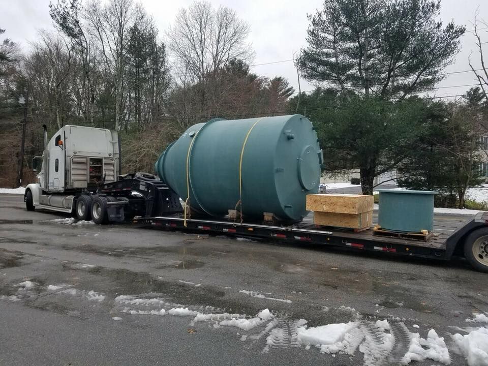 A semi truck is carrying a large tank on a trailer