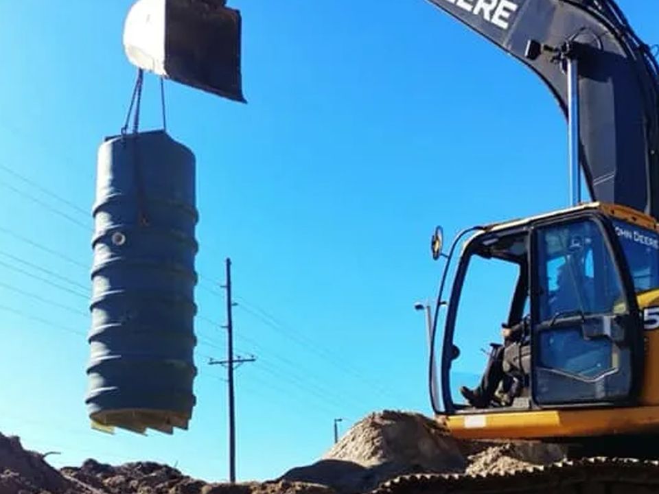 A john deere excavator is lifting a large object