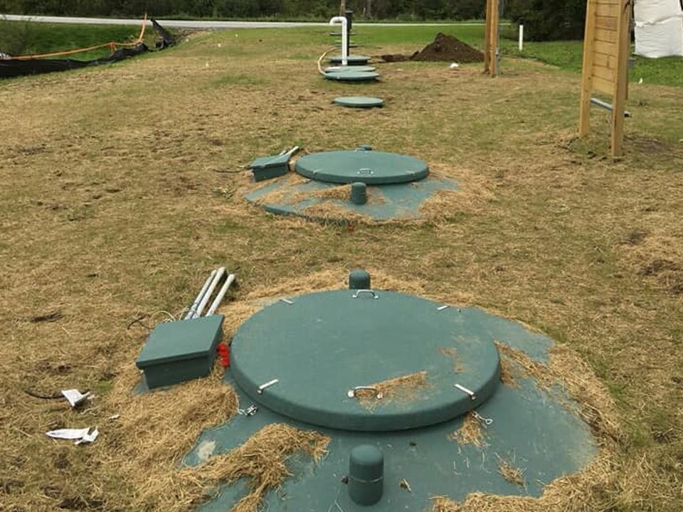A row of septic tanks are sitting in the middle of a grassy field.