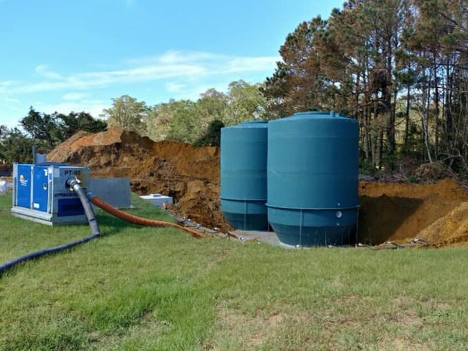 Two large blue tanks are sitting in the middle of a grassy field.