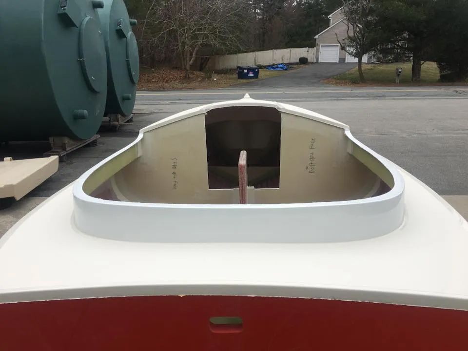 A red and white boat is sitting in a parking lot