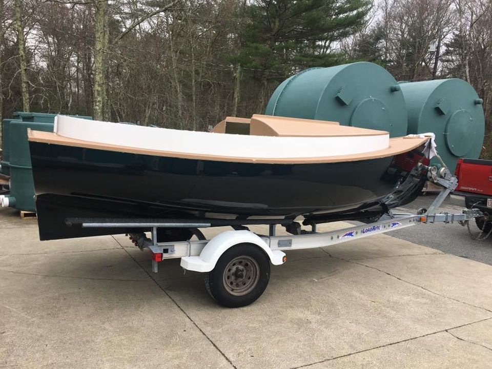 A small boat is on a trailer in a parking lot