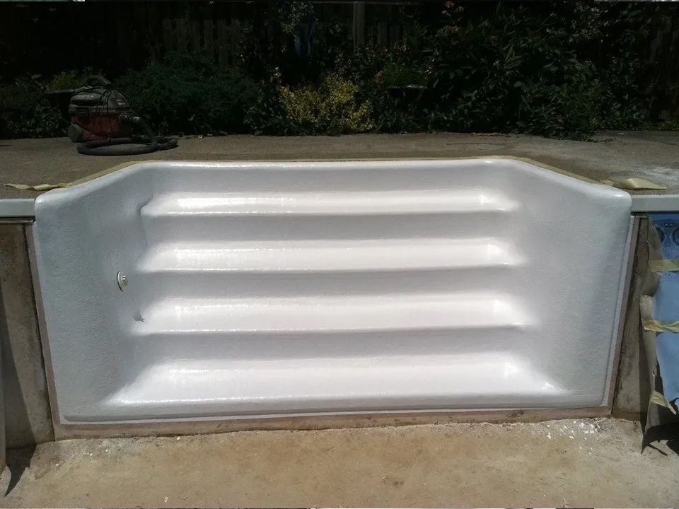 A white staircase is being built into a swimming pool.
