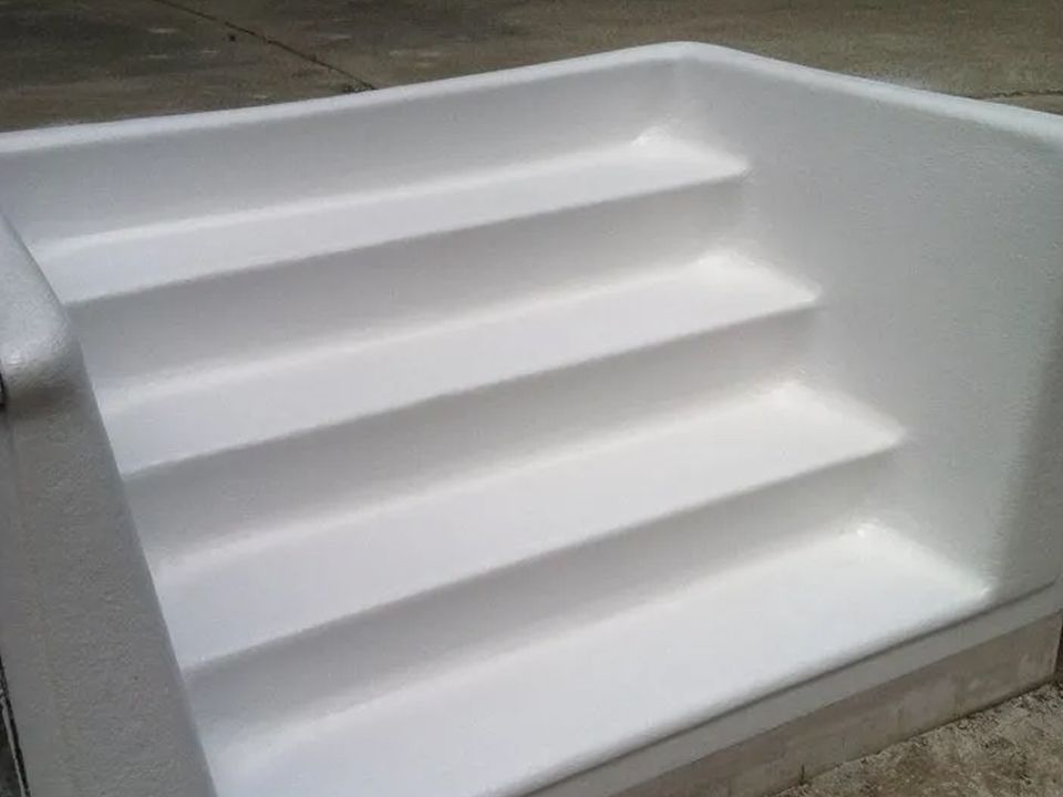 A white staircase is sitting on top of a concrete surface.