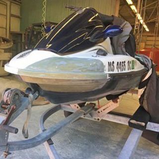 A jet ski is sitting on a trailer in a garage.