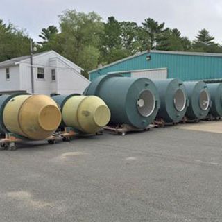 A row of barrels are lined up in a parking lot in front of a building.