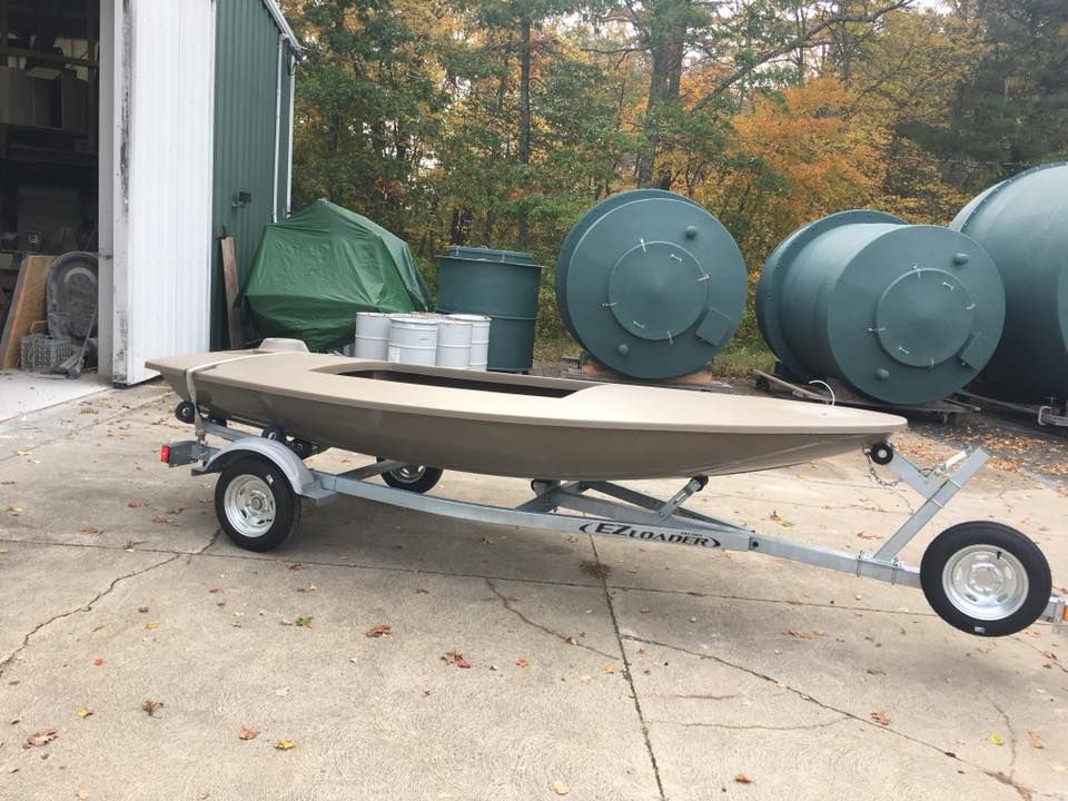 A boat is on a trailer in front of a garage.