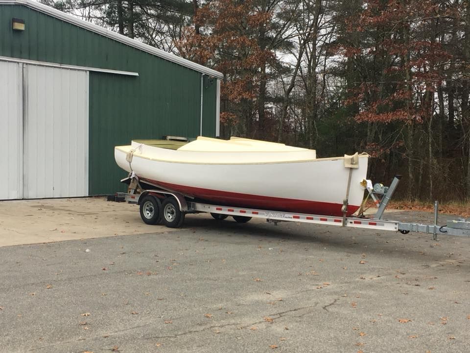 A boat is on a trailer in front of a green building