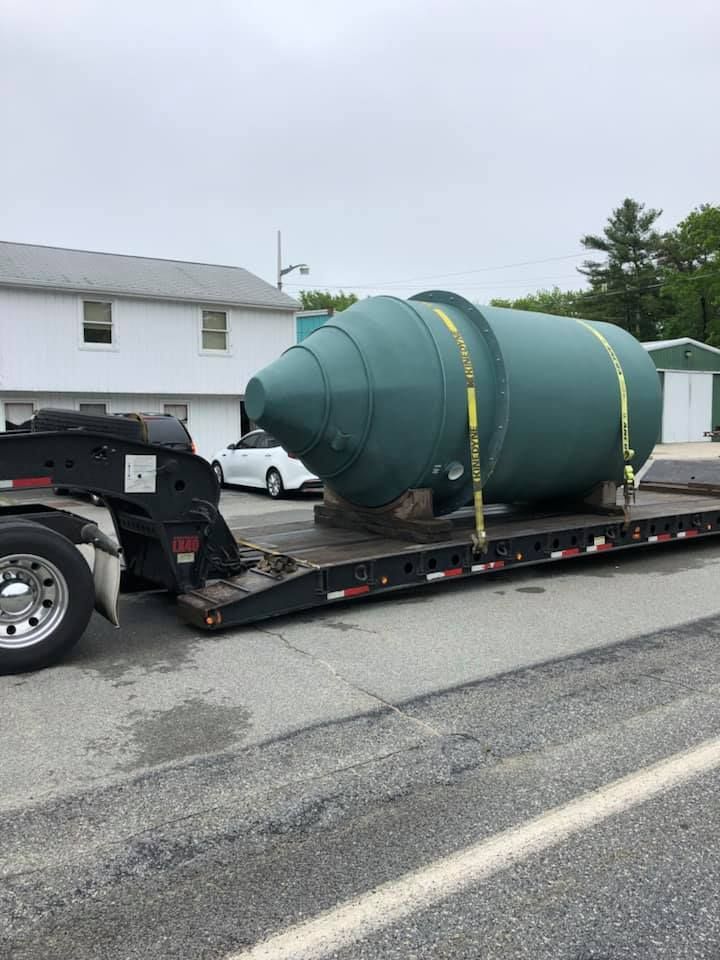 A large green tank is sitting on top of a trailer.