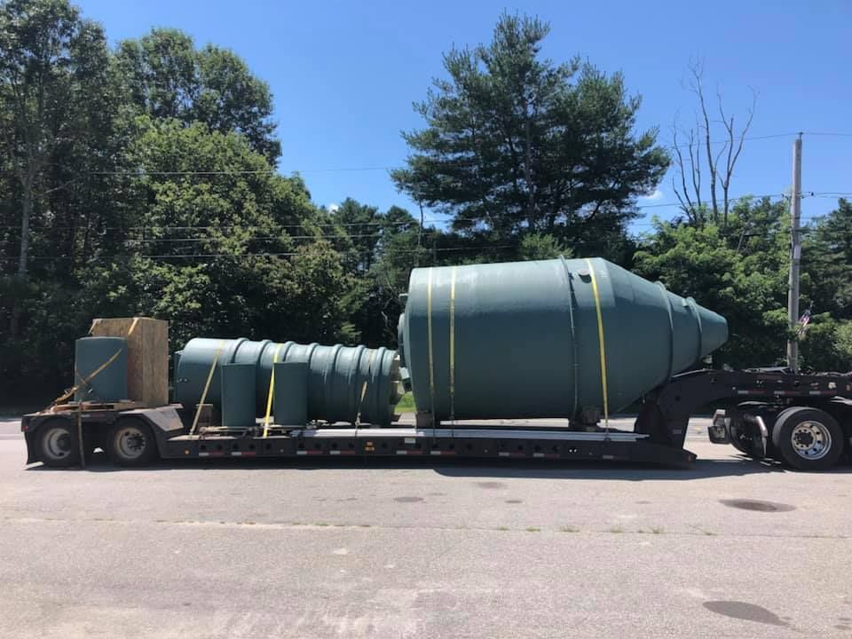 A large green container is being transported on a trailer