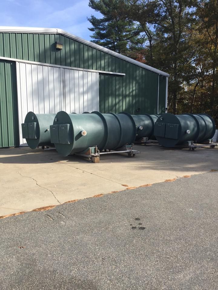 A row of green pipes are sitting in front of a green building.