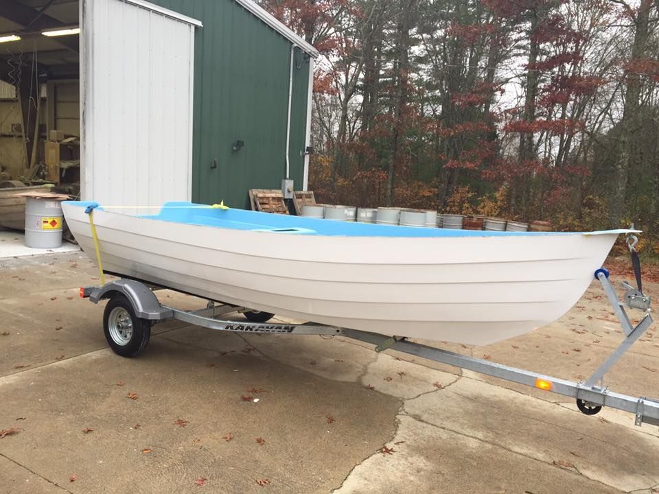 A small boat is on a trailer in front of a building.