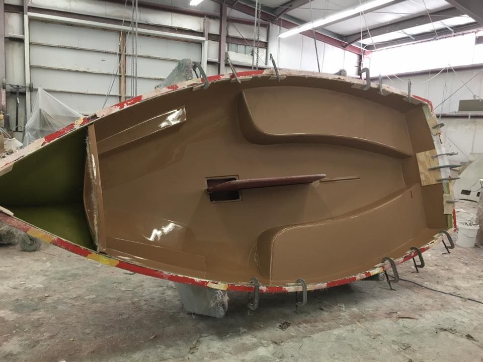 A boat is being built in a factory and is sitting on the floor.