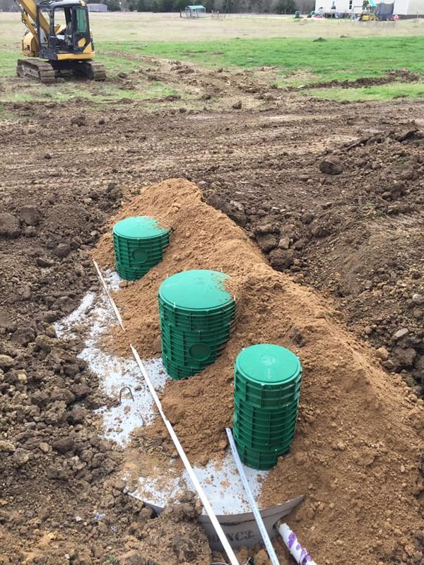 A septic system is being installed in a dirt field.