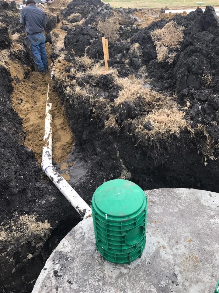 A man is standing in the dirt next to a green bucket.