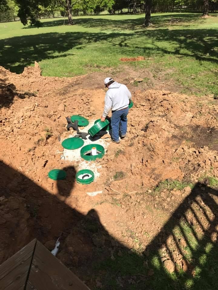 A man is working on a septic system in a yard.