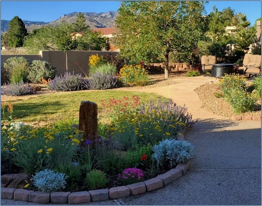 Lush garden with winding path, diverse flowers, and a mountain backdrop.