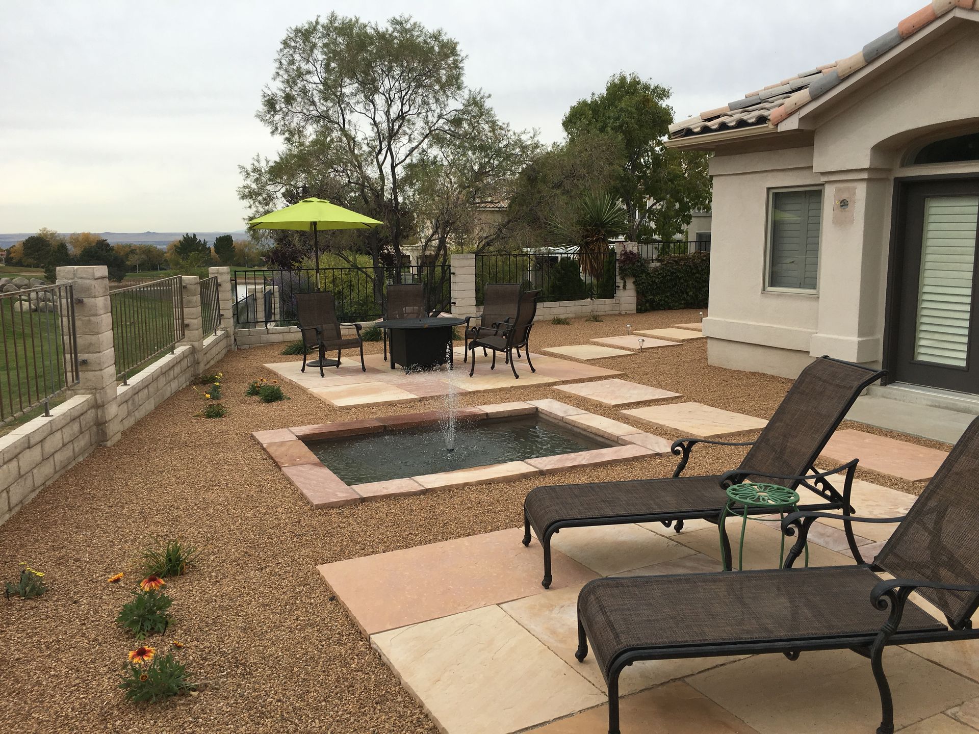 Patio with water feature, lounge chairs, and seating area next to a house.