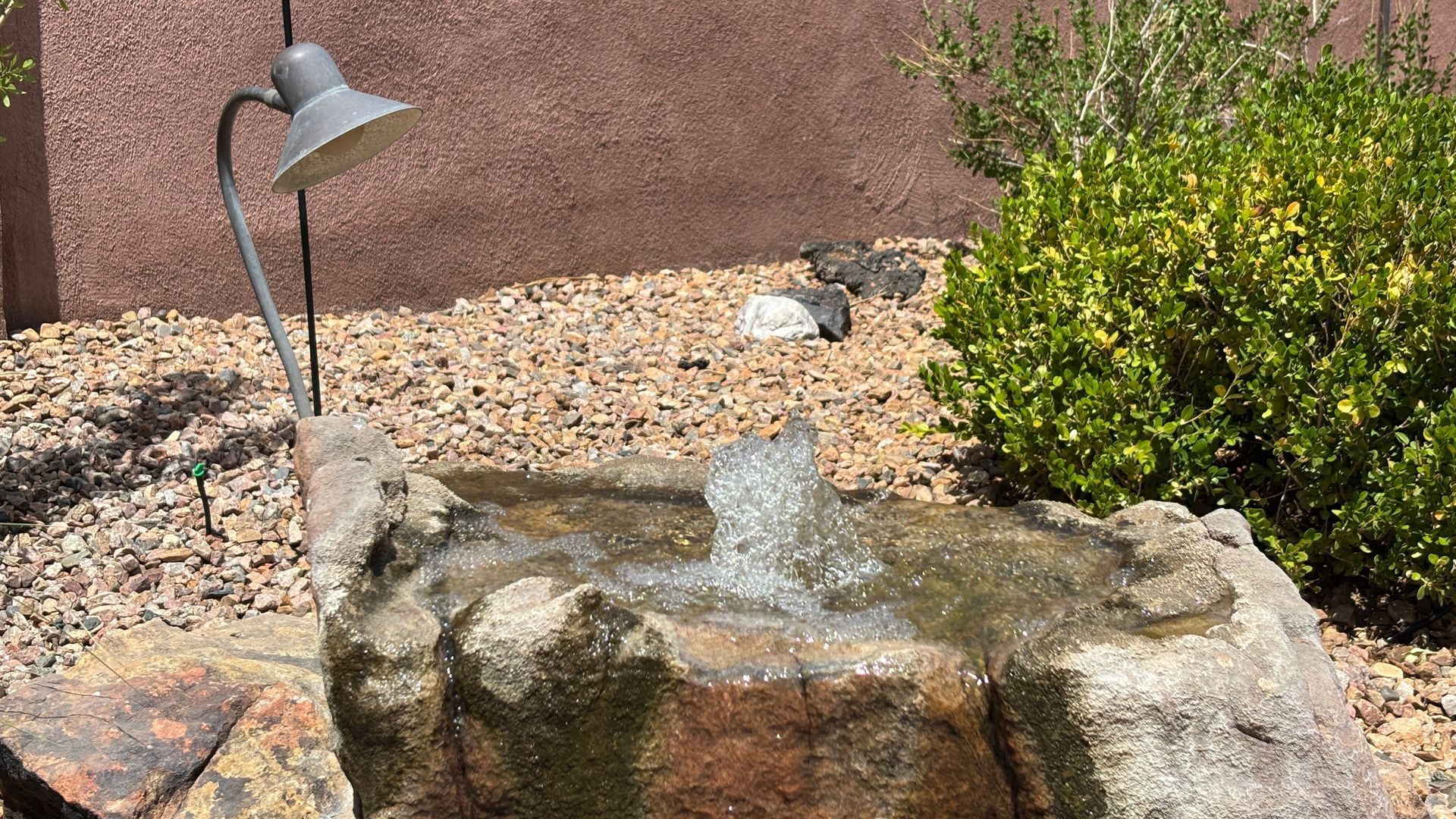Water fountain with a rock exterior in a garden setting.