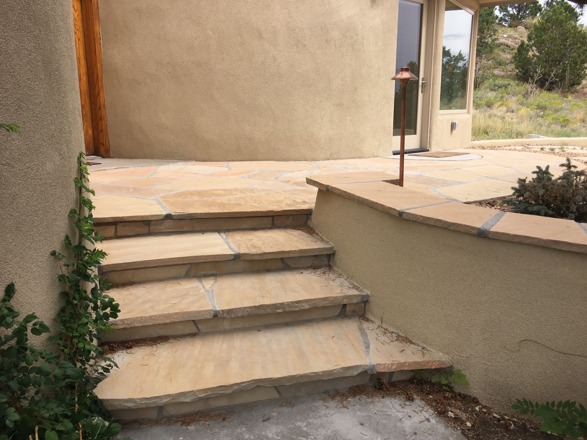 Stone steps lead to a rounded, stucco-textured building entrance.