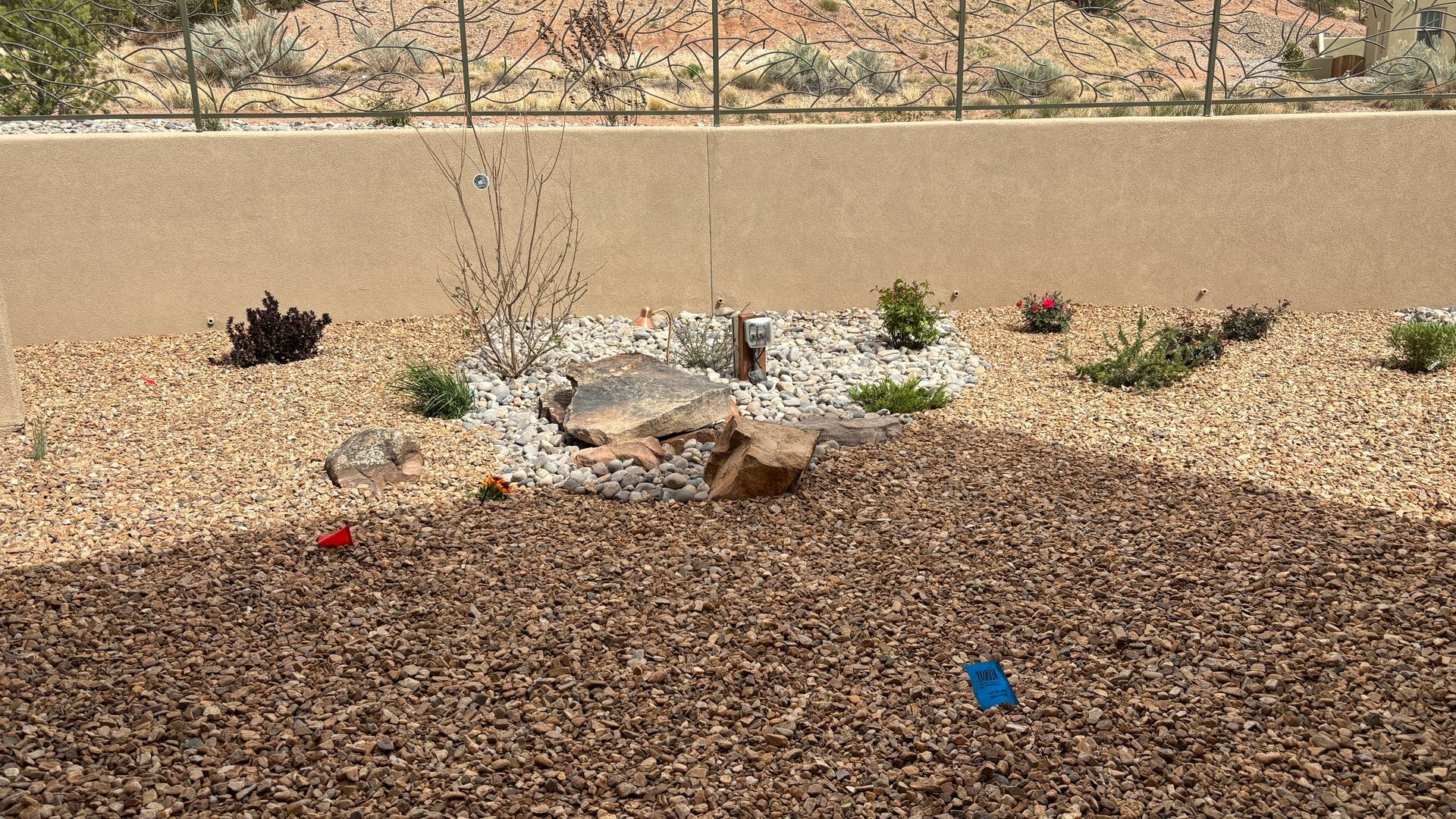 Rock garden with brown mulch and beige wall.