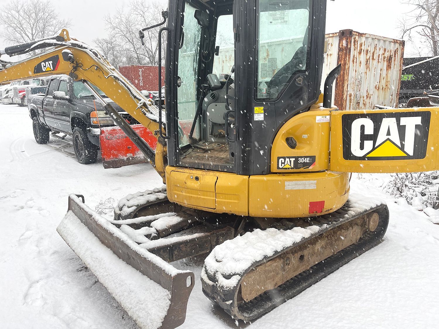 A yellow and black excavator in the snow