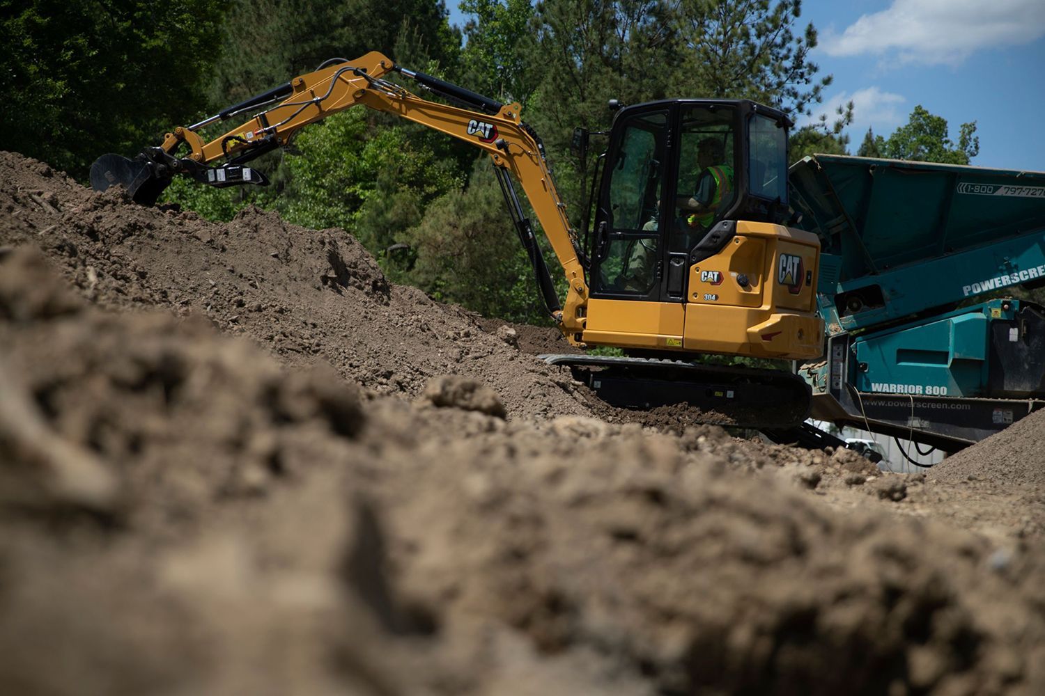 A mini excavator is sitting on top of a pile of dirt