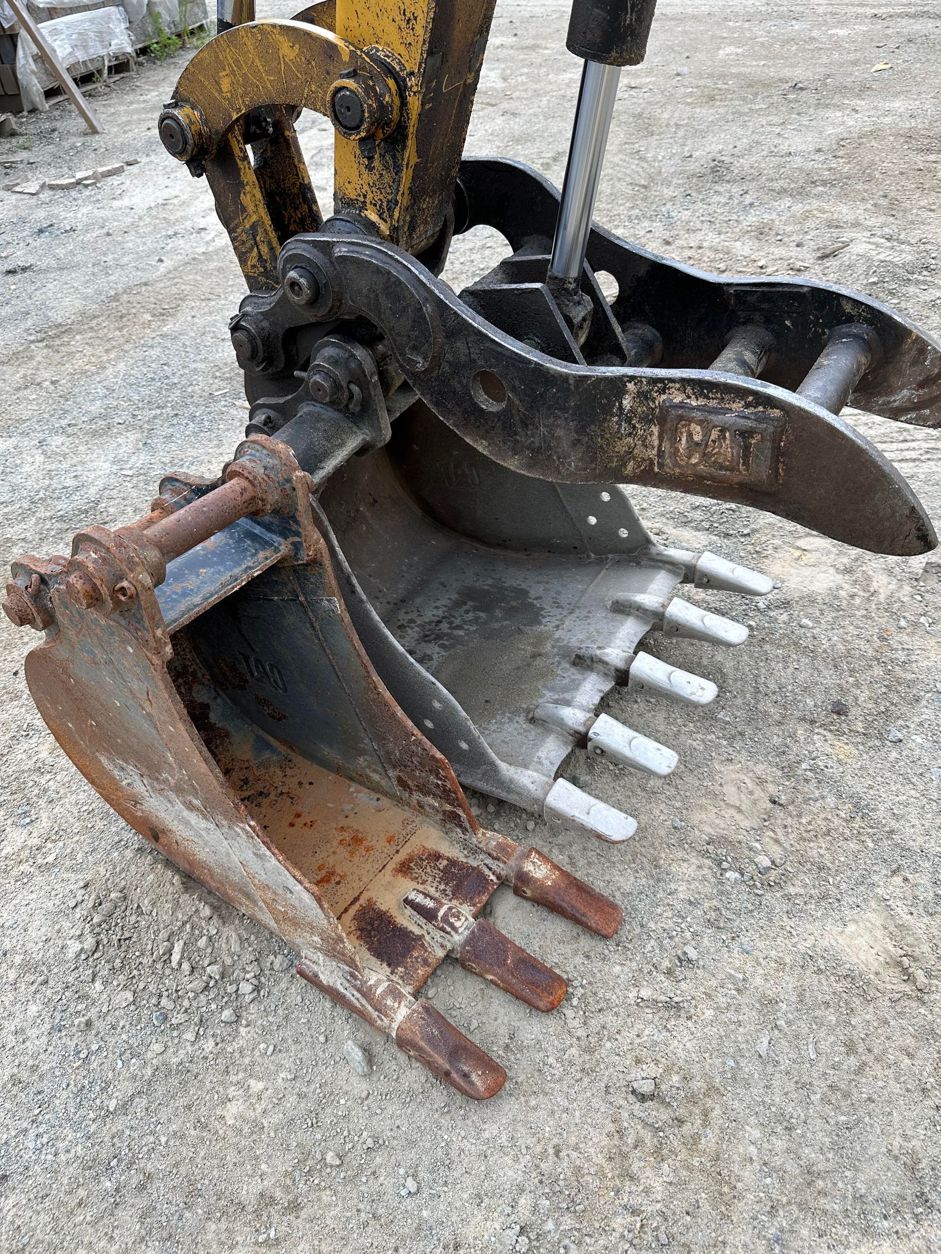 A close up of a rusty excavator bucket on the ground.
