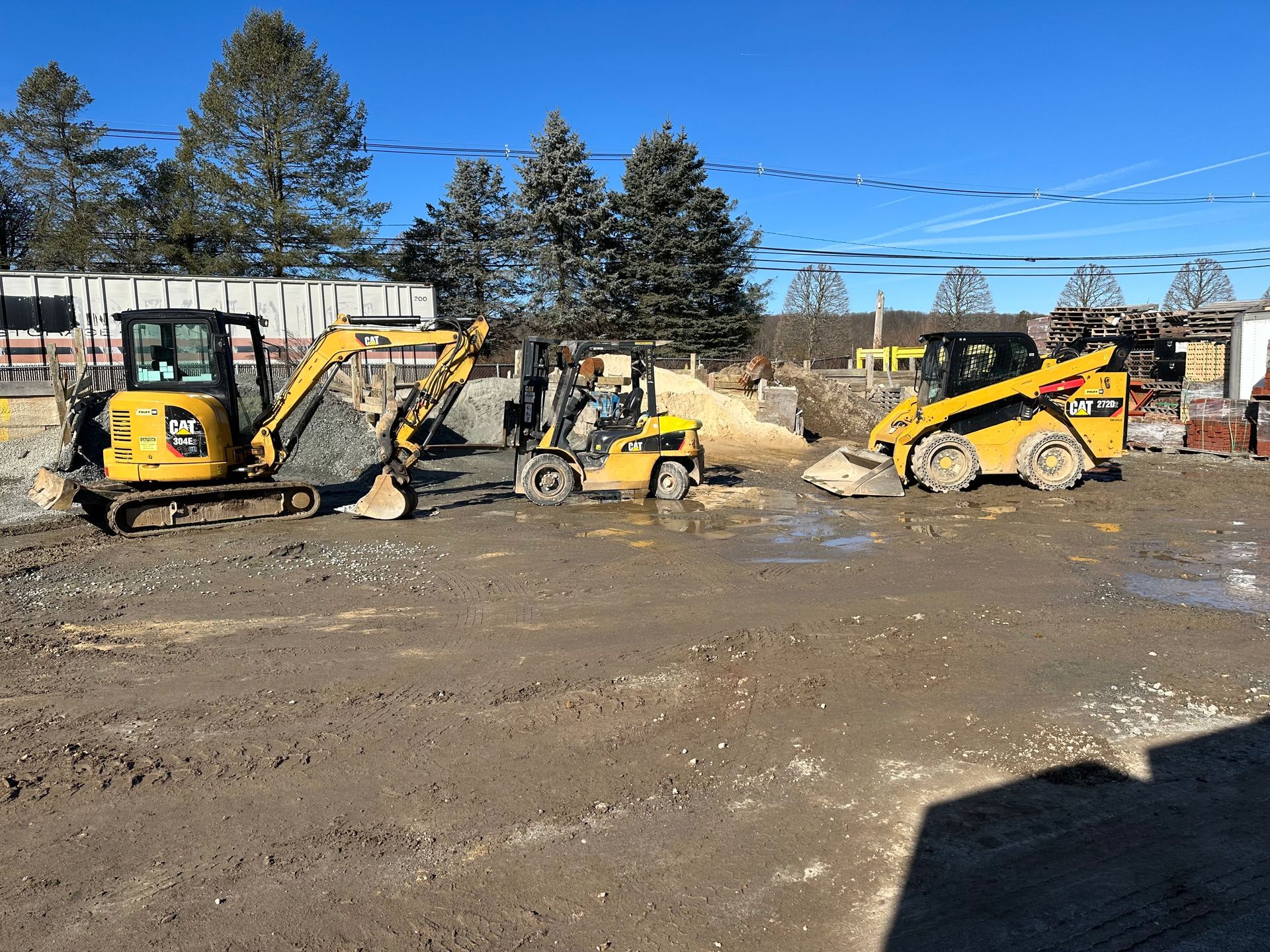 A group of construction vehicles are parked in a dirt lot.