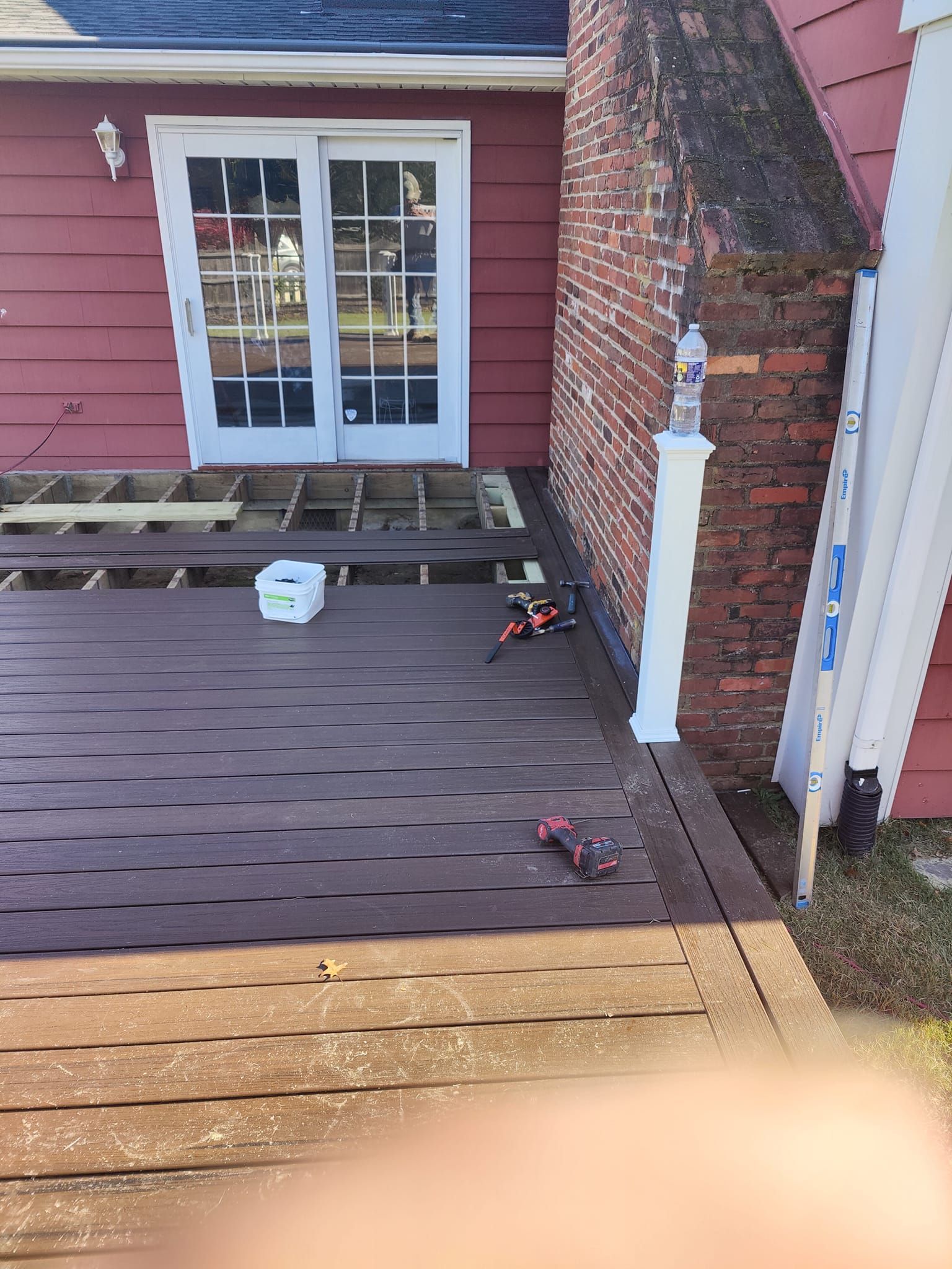 A wooden deck is being built in front of a red house.